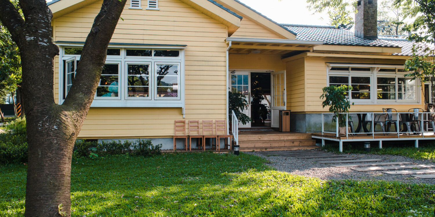 charming-yellow-house-with-wooden-windows-green-grassy-garden Eco-friendly home remodel featuring solar panels and reclaimed wood flooring